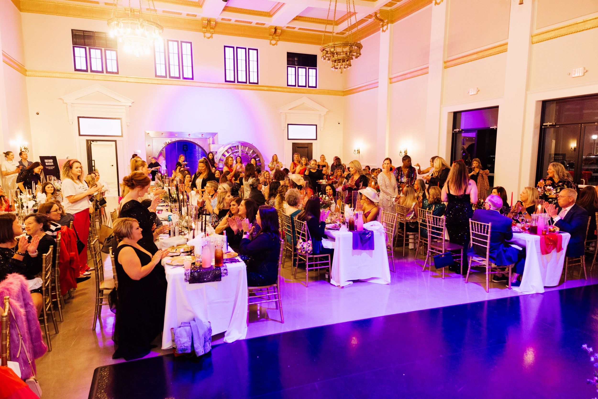 Branding and event session with wide view of an elegant event space with purple uplighting and guests mingling.