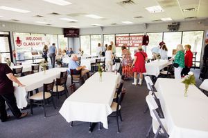 Conference room set up with white tablecloths and chairs for a business gathering.