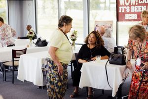 Event space with 'WOW' banner and attendees mingling around tables.
