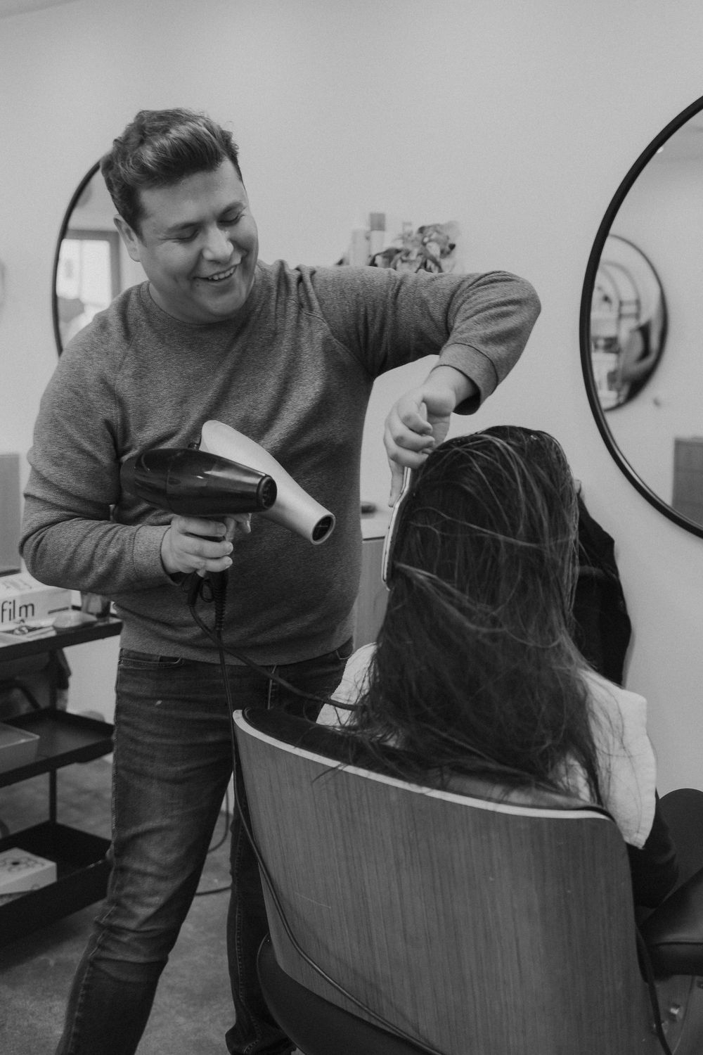 Stylist using hair dryer and brush during salon service.