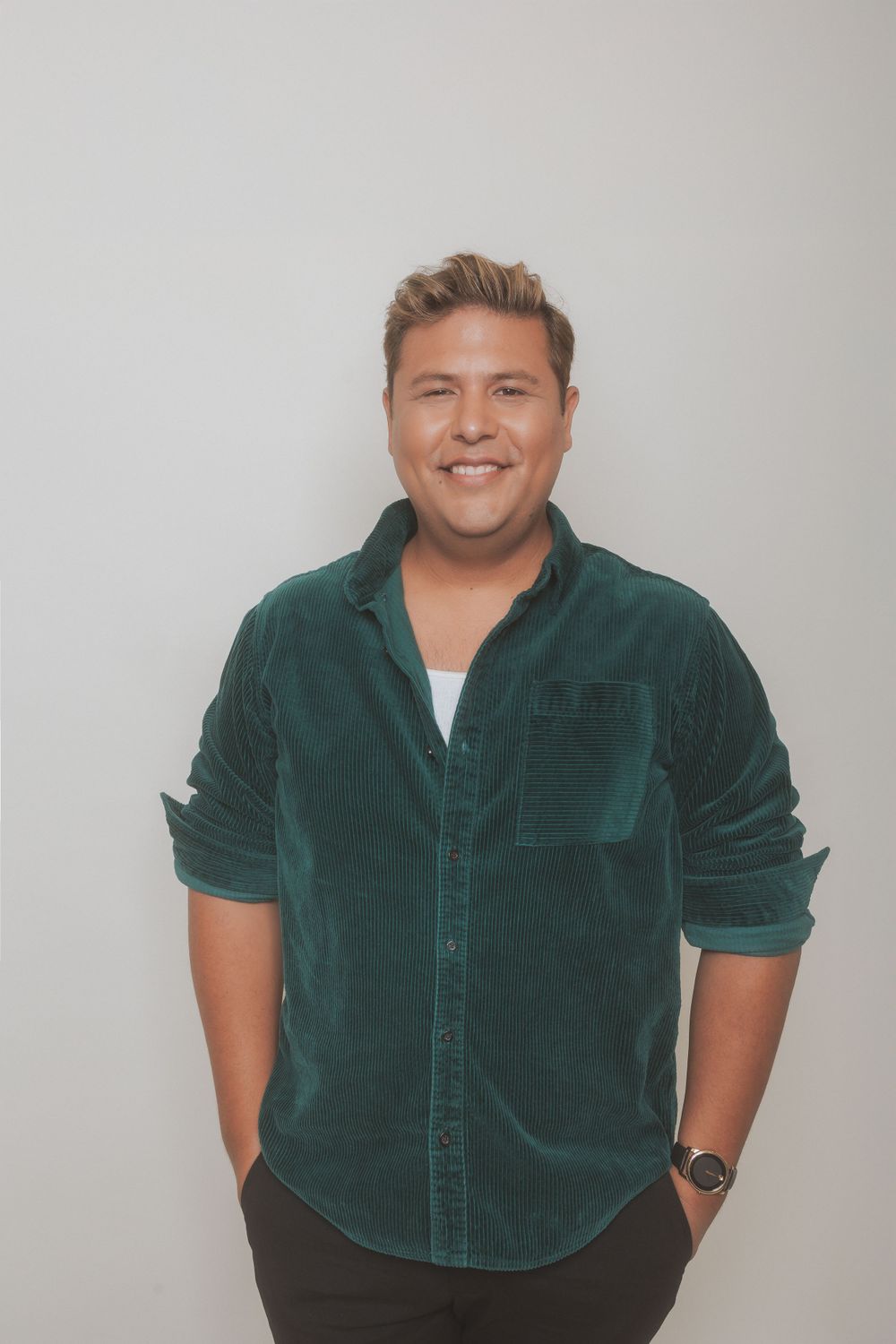 Professional in green corduroy shirt posing against plain background.