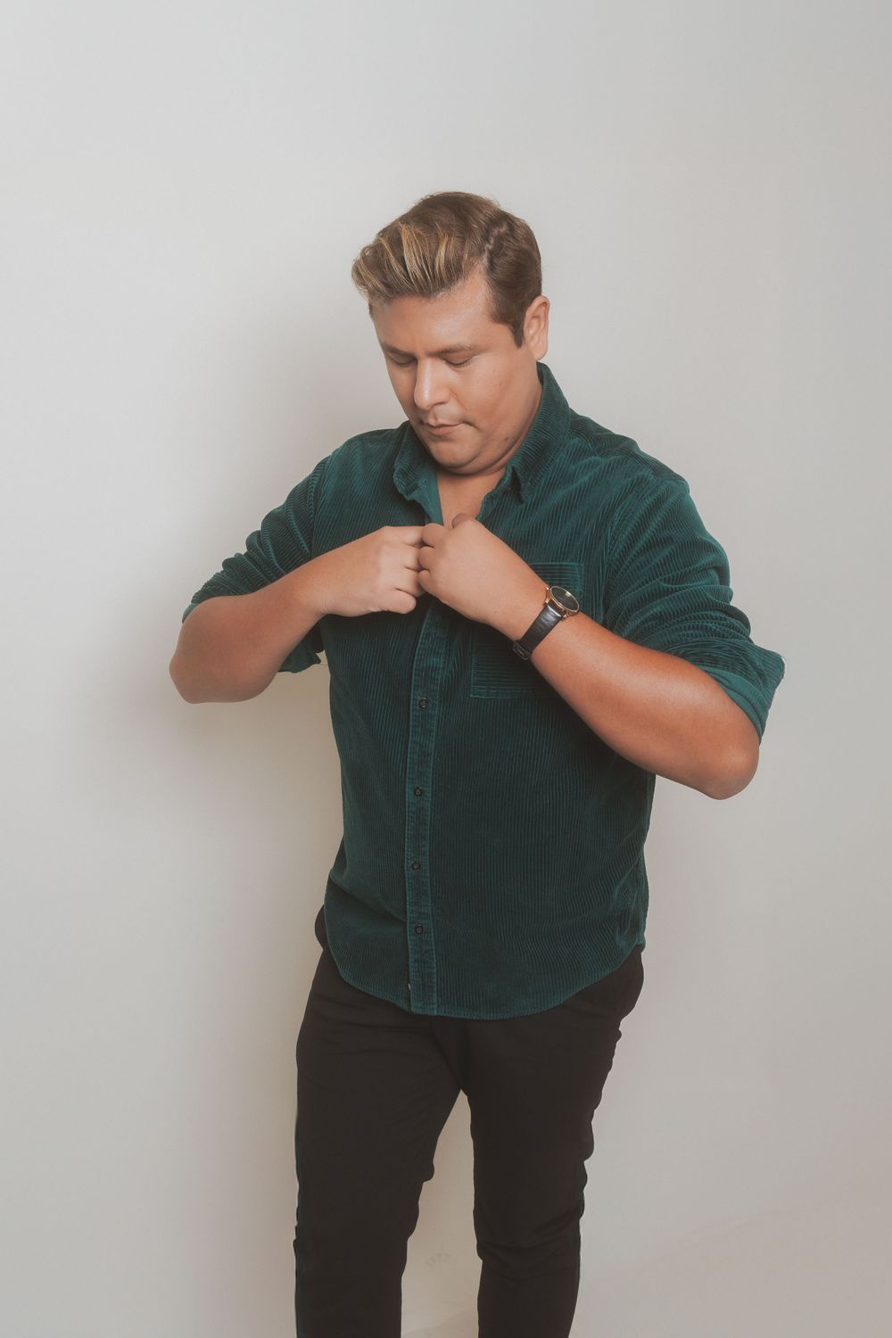 Fashion portrait of person adjusting green corduroy shirt collar.