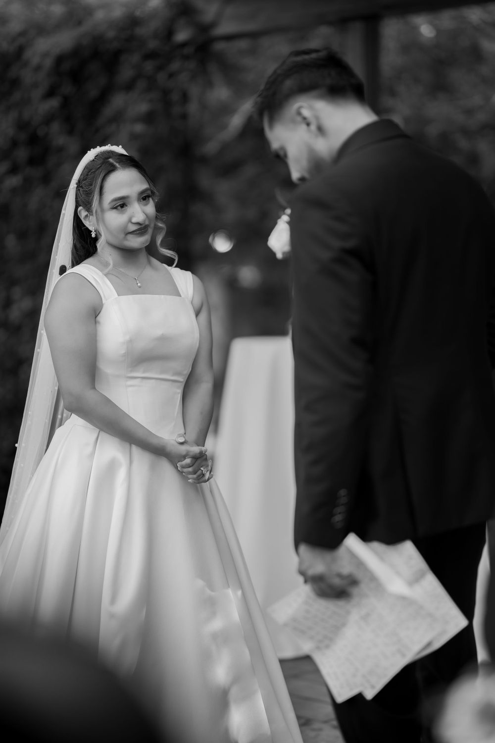 Black and white photo of a wedding ceremony showing the couple during their vows.