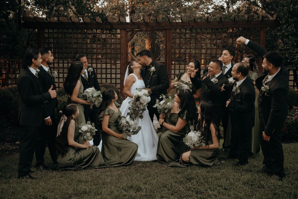 Wedding party gathered for group photos against a brick wall backdrop.