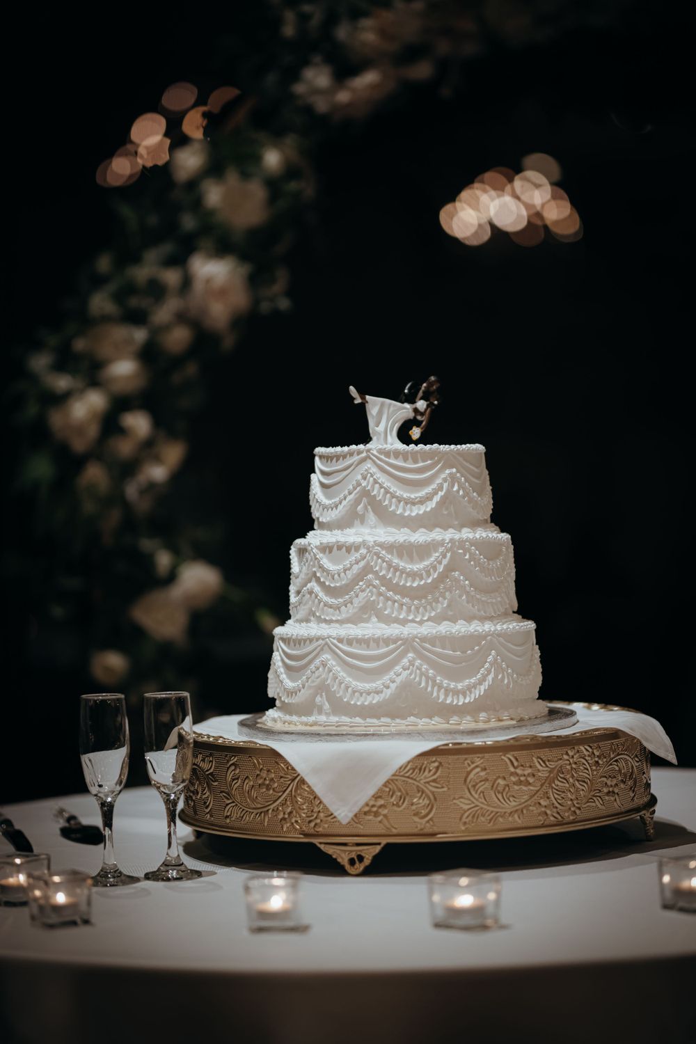 Elegant white wedding cake with delicate piped details and pearl accents on display.