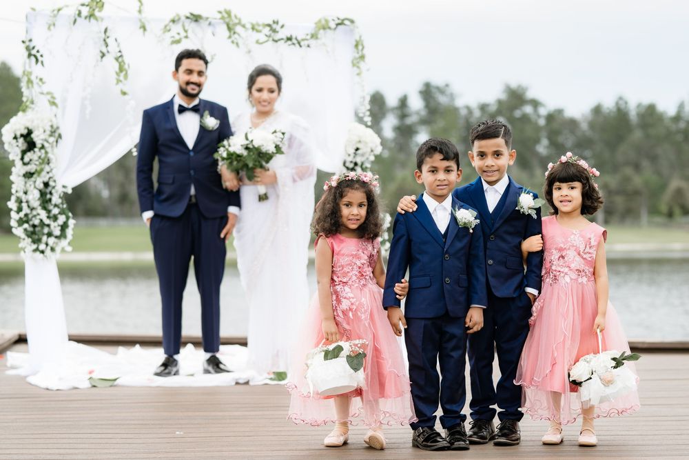 Wedding party in navy and pink attire posed on wooden dock by lake.