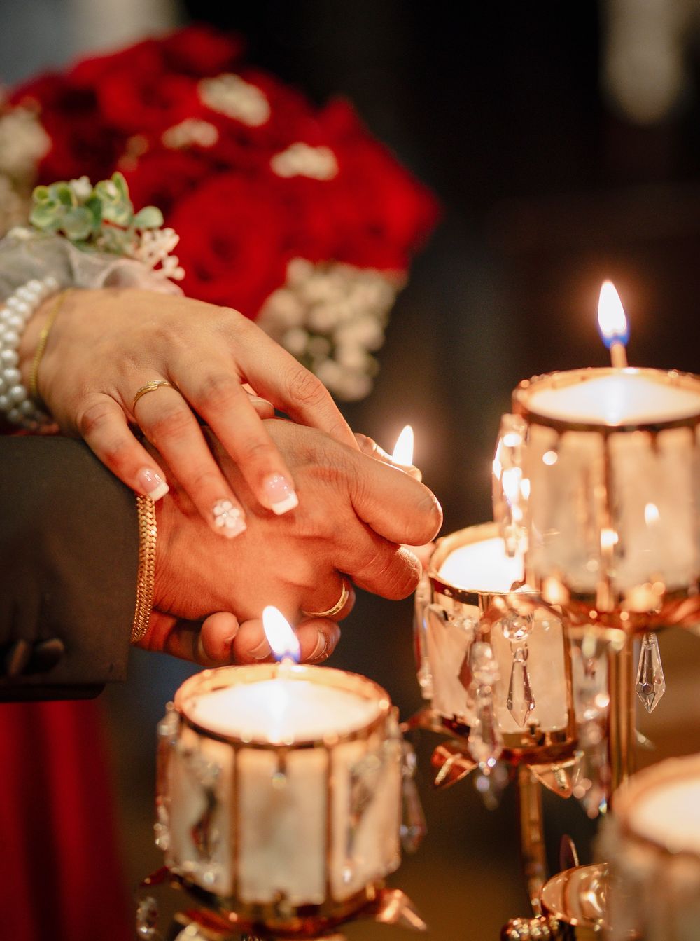 Close-up of hands near glowing candles creating romantic wedding ambiance.