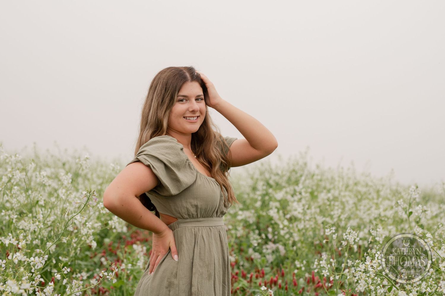 Model in sage dress strikes confident pose in a wildflower field during golden hour.