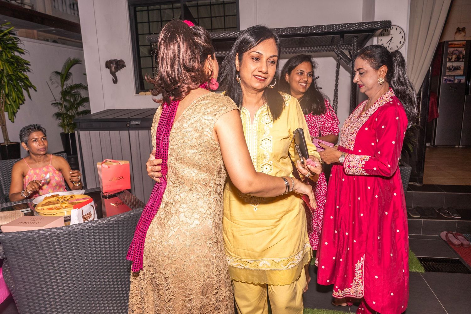Group of guests in colorful traditional attire socializing at an indoor celebration party.