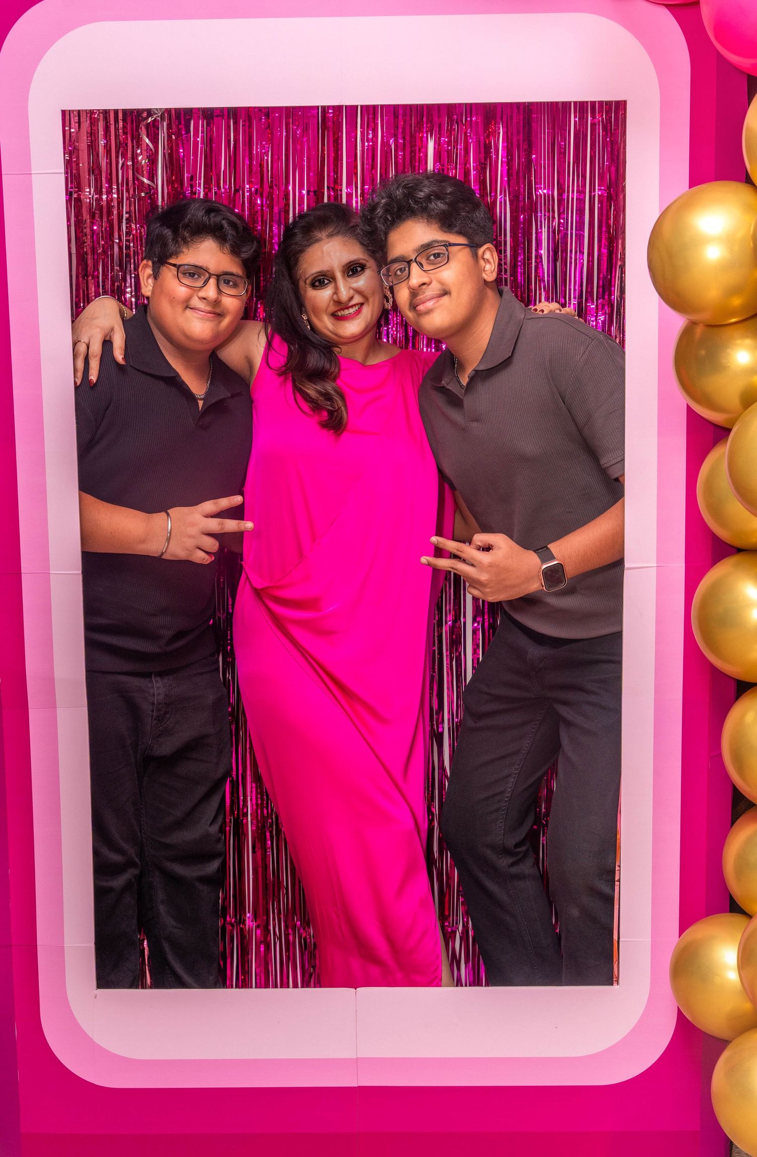 Party photo with pink metallic backdrop and gold balloon decorations at a celebration.