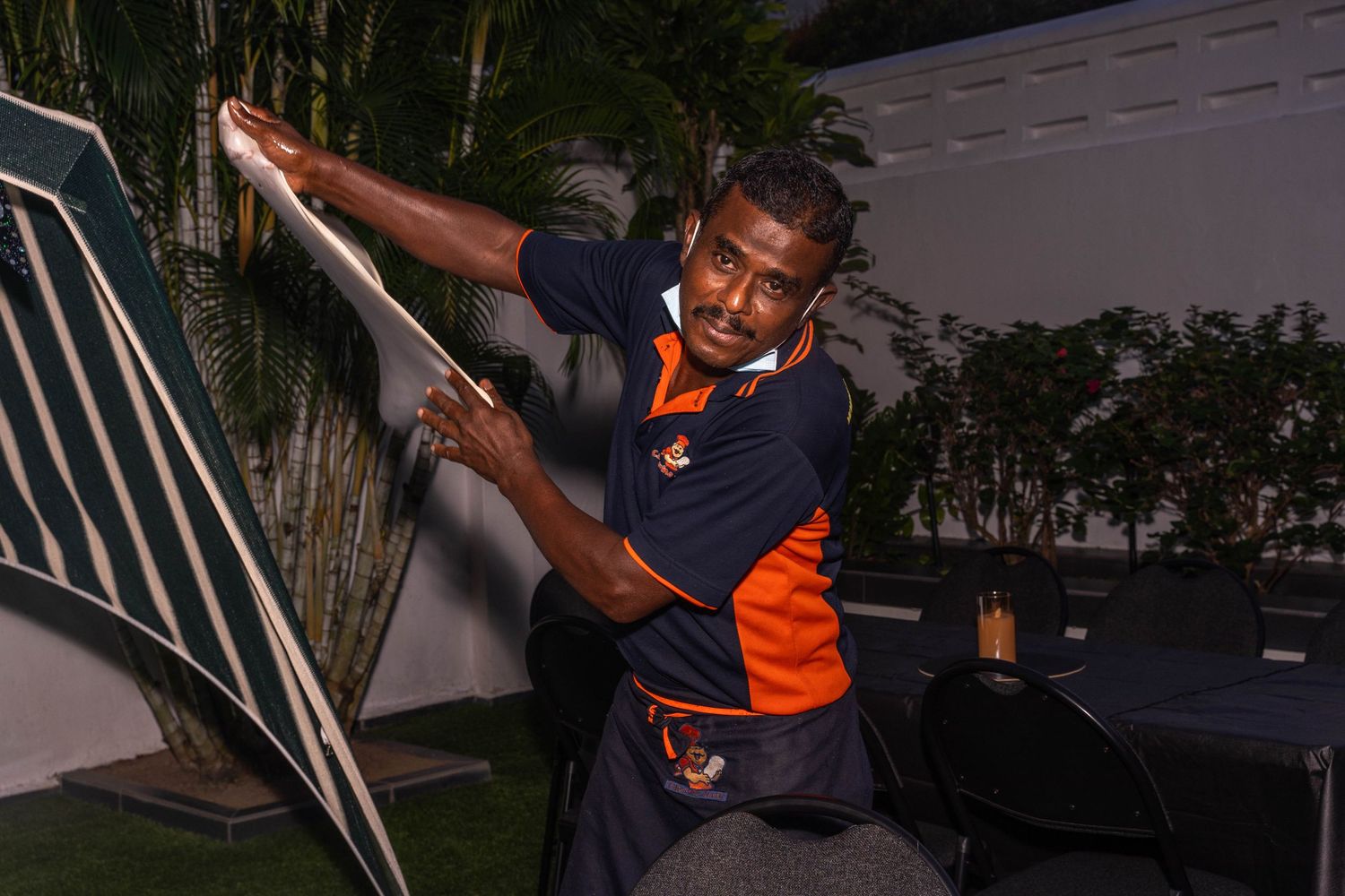 Chef in orange uniform working outdoors at night with equipment.
