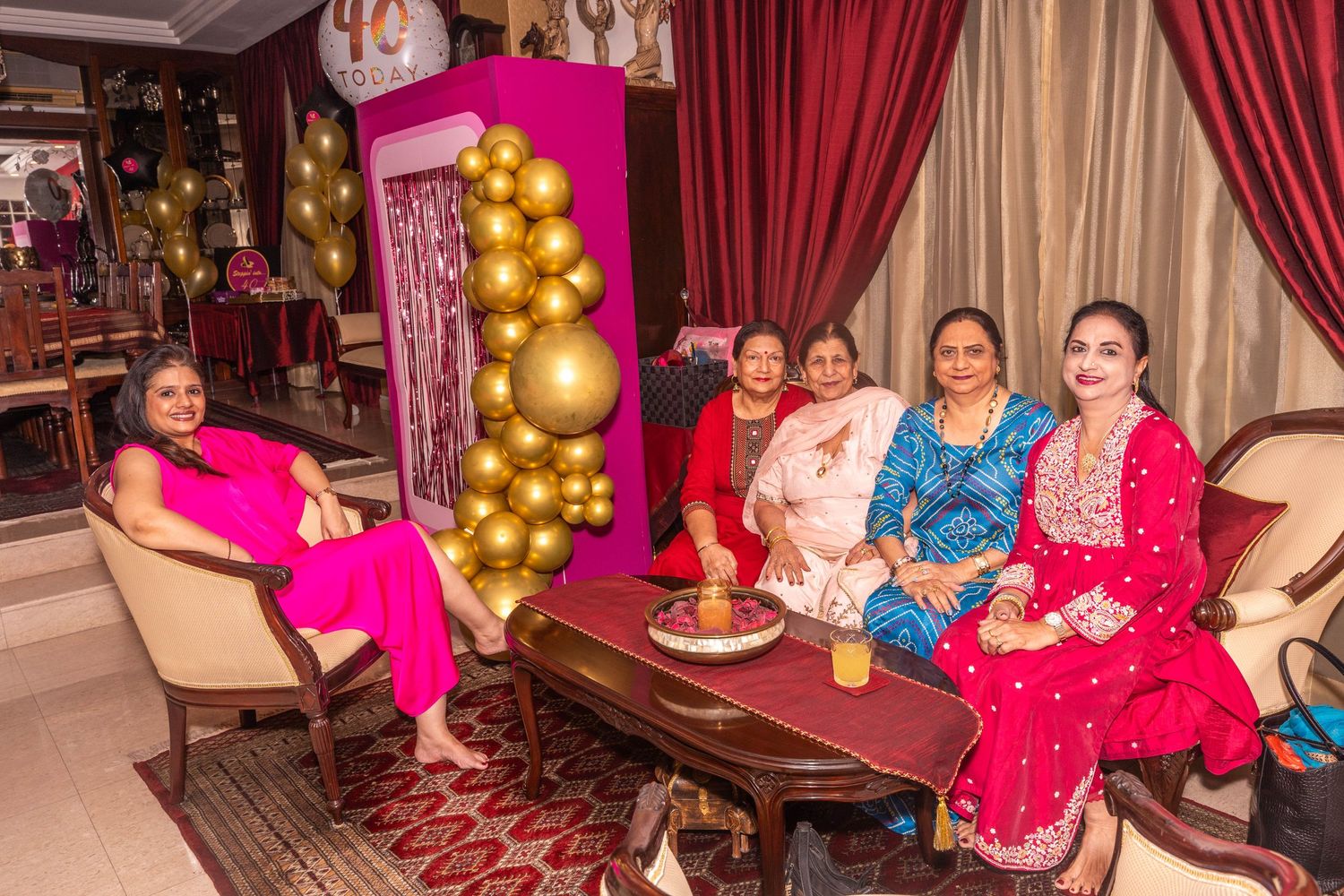 Festive gathering with pink and gold decorations in luxurious room setting.