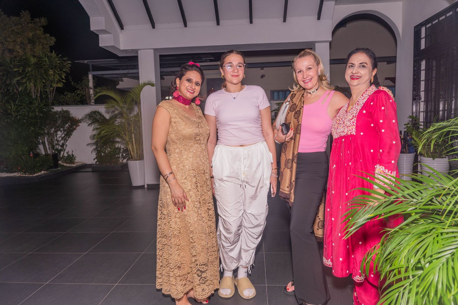 Group photo at an evening celebration with potted plants and arched architecture in the background.