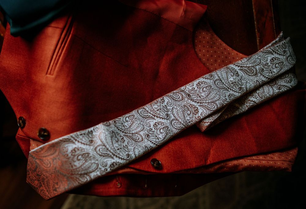 Elegant gray paisley tie laid out on red fabric background.