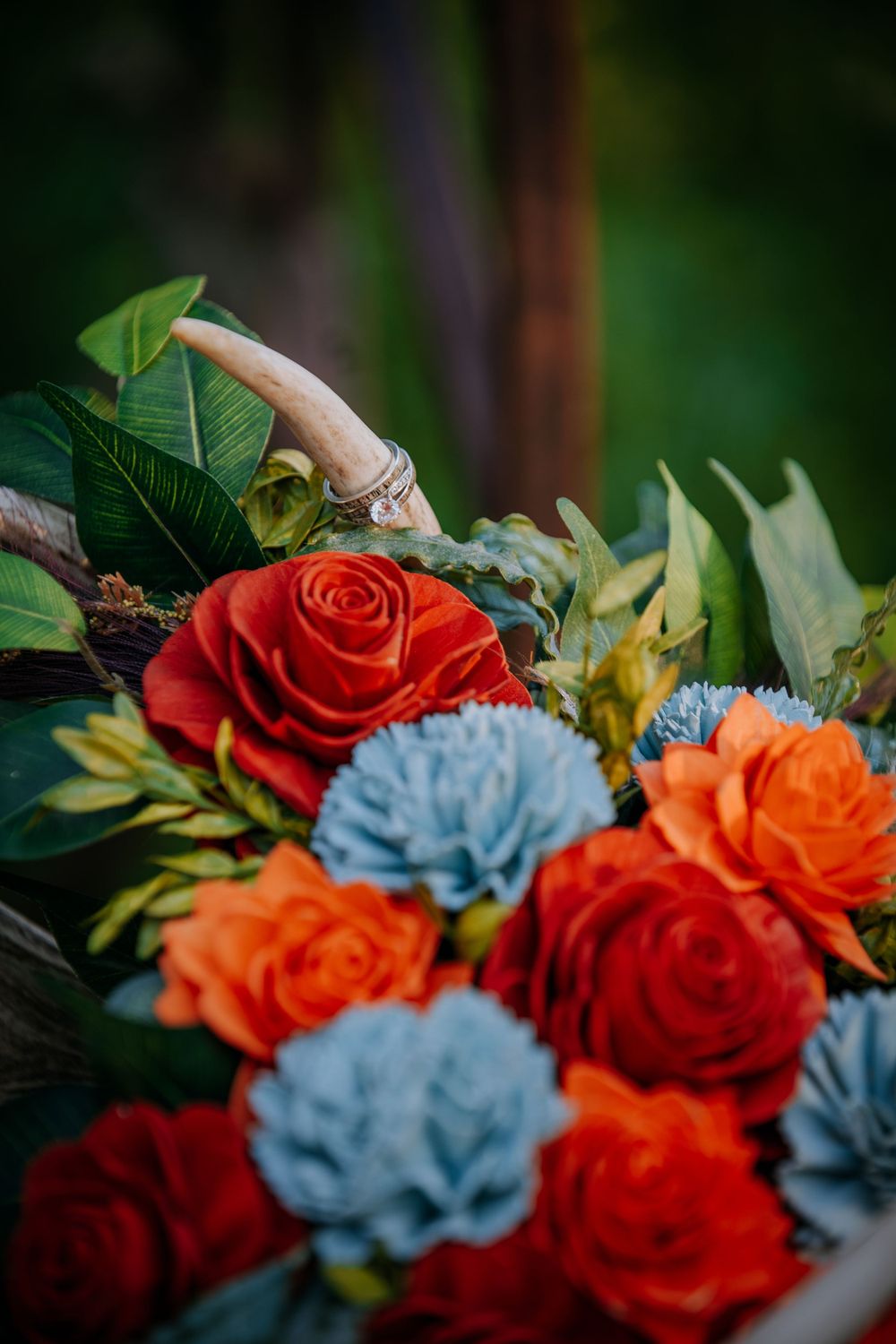 Close-up of floral arrangement showing detailed red roses and light blue flowers with green foliage.