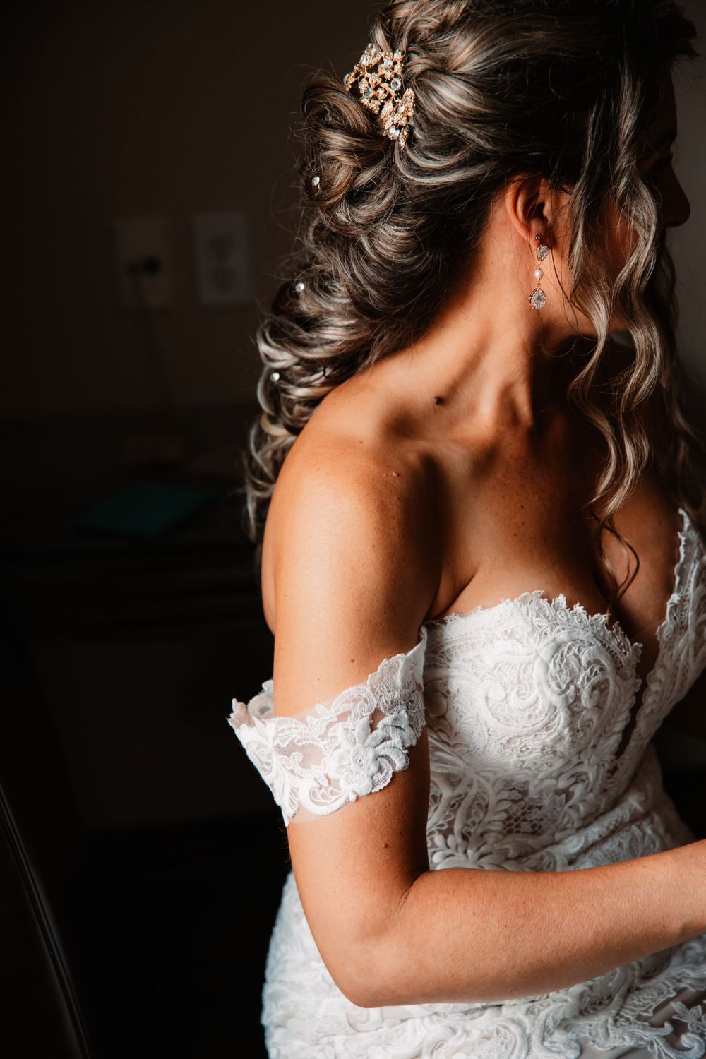 Close-up detail of bridal hairstyle with crystal hair accessory and lace wedding dress.