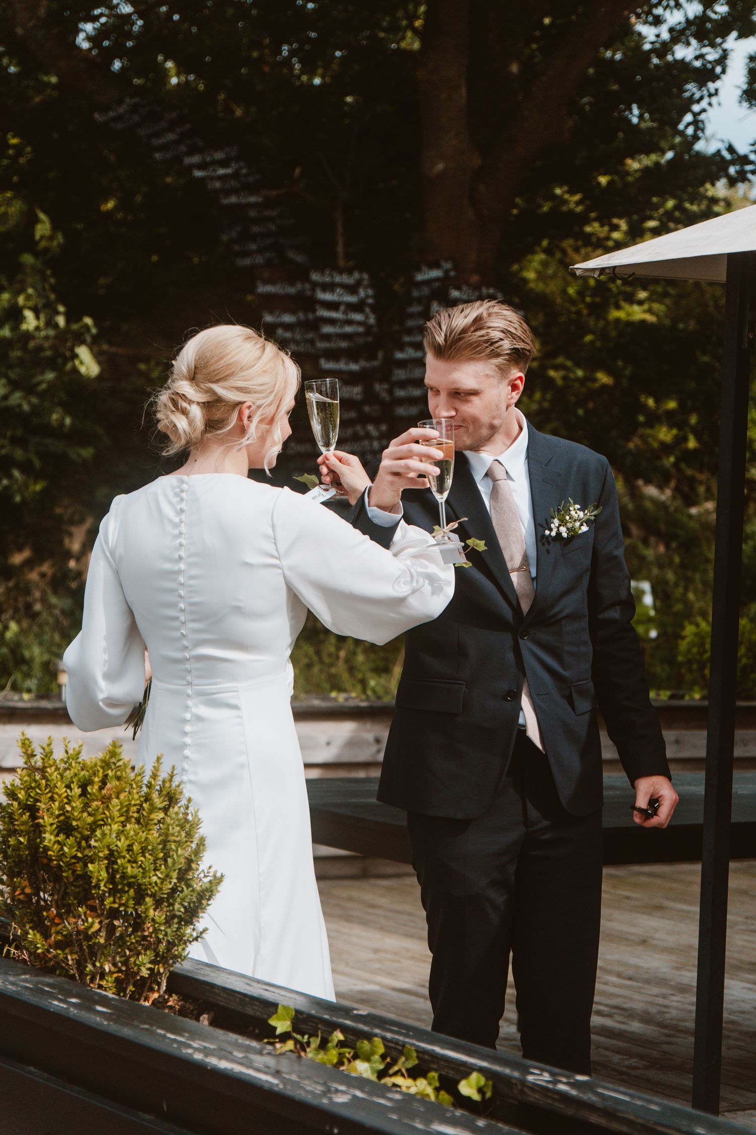 Wedding couple sharing a celebratory champagne toast outdoors.