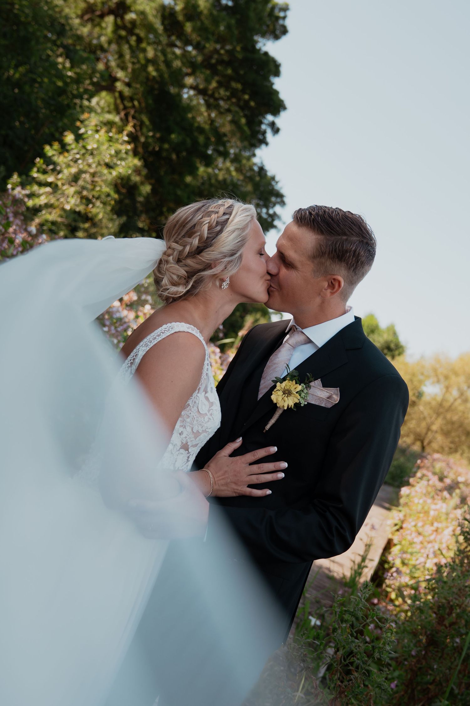 Newlyweds share an intimate moment in a sunlit garden setting.