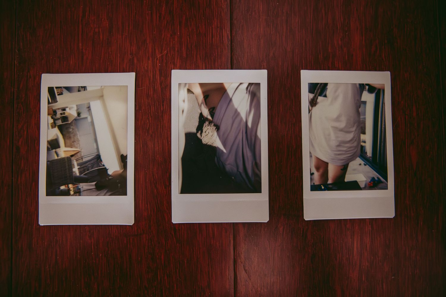 Three vintage polaroid photographs laid out on a dark wooden surface.