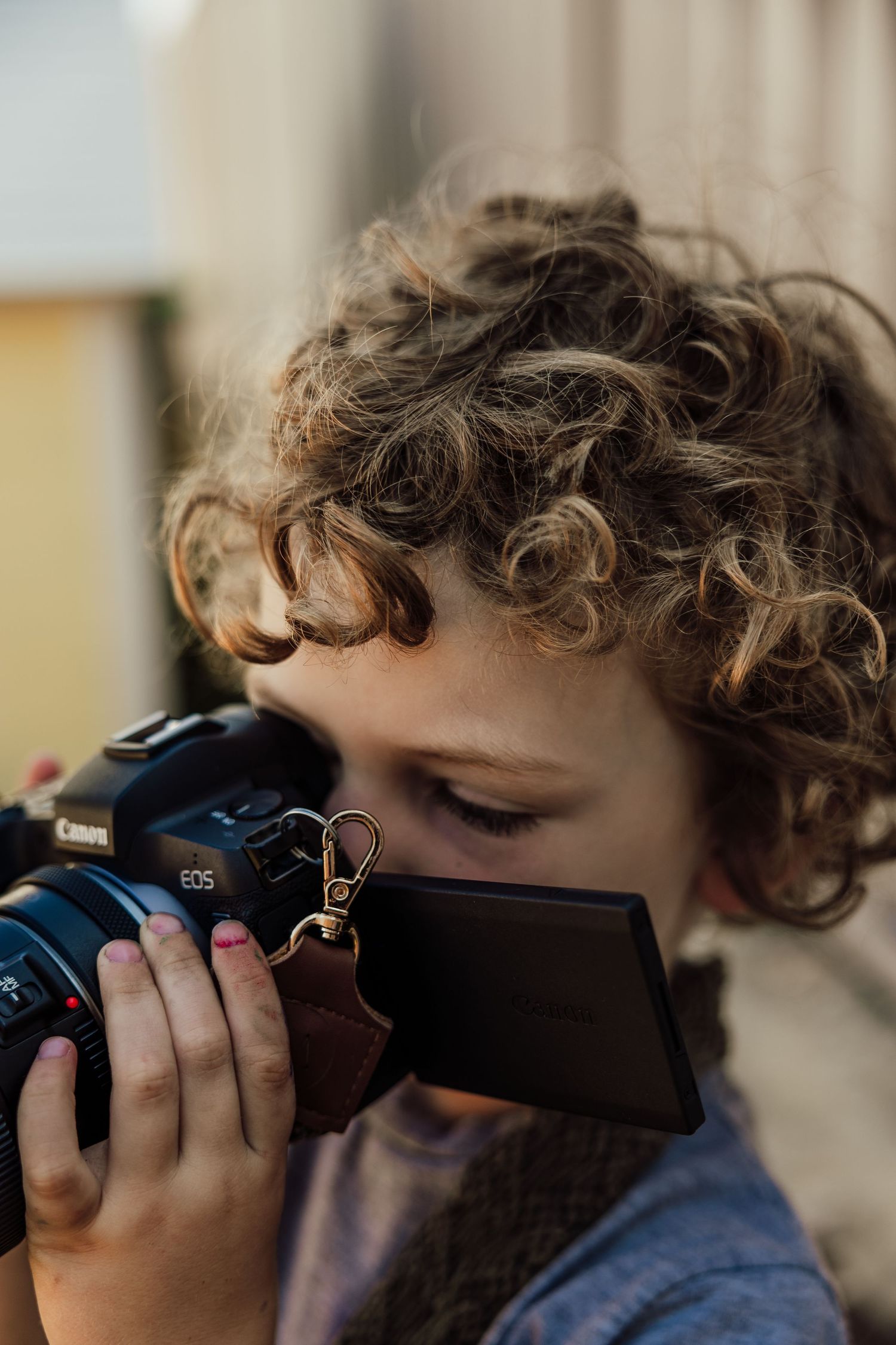 Close-up of hands holding Canon camera while taking photo.