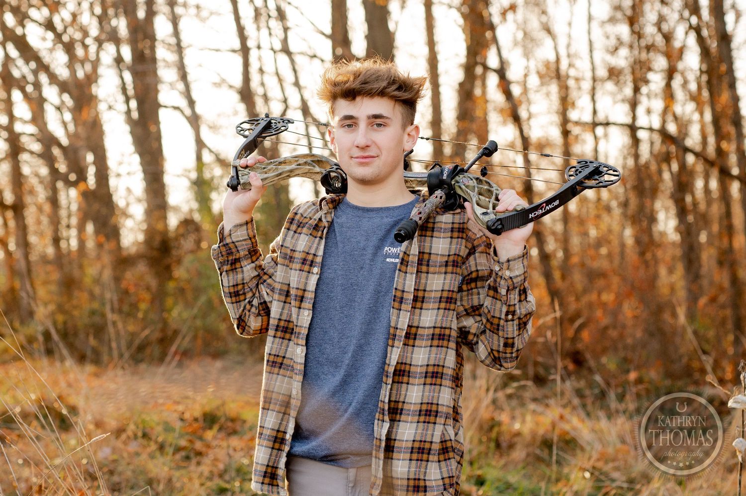Person displaying compound bow equipment while wearing plaid shirt in forest setting.
