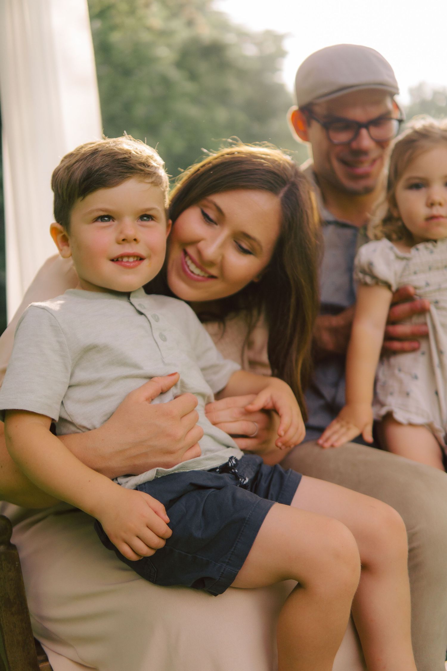 A family enjoying a warm sunset moment together outdoors in neutral and creamy tones.