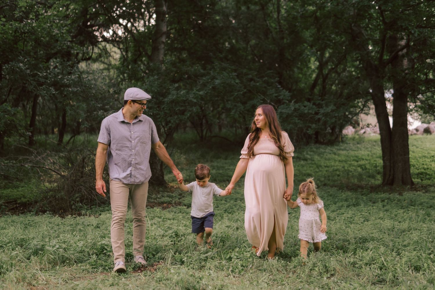 A family walking together and holding hands in a lush green forest setting during a summer afternoon in South Austin.