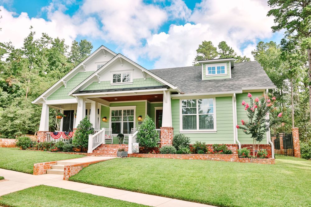 Craftsman style house with sage green siding and front porch featuring white columns.