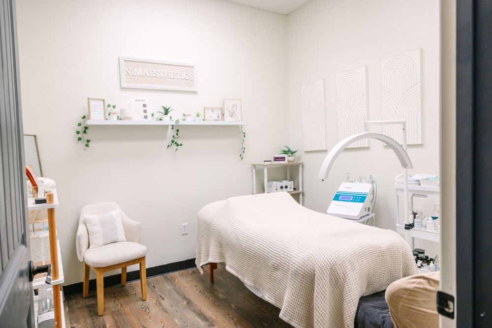 Clean, minimalist treatment room with massage bed, medical equipment and soft lighting.