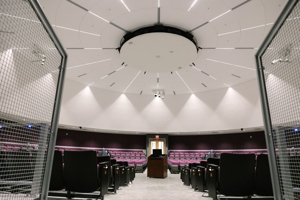 Modern auditorium with dramatic sunburst ceiling design and symmetrical lighting pattern.