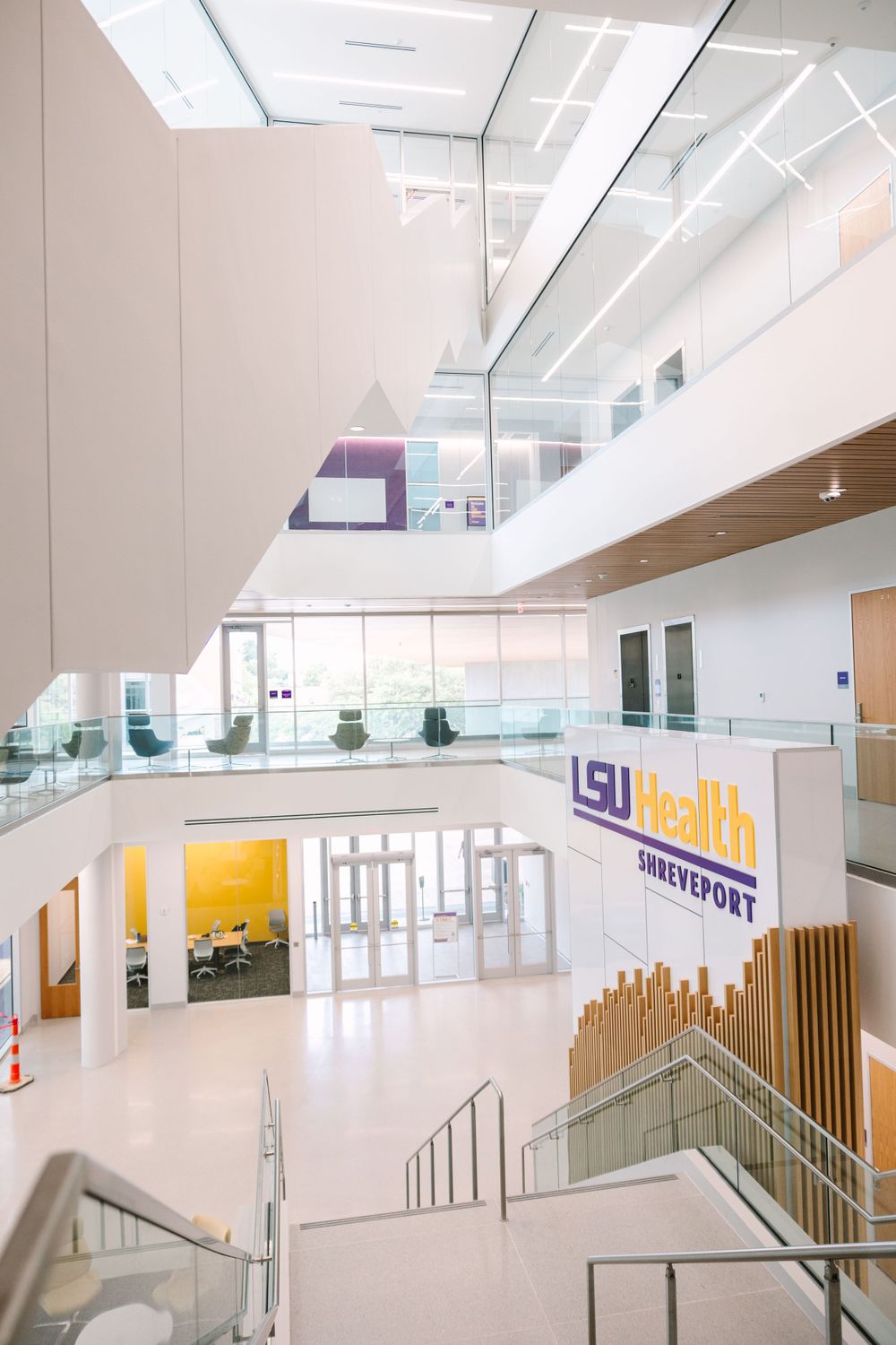 Modern two-story building interior with white walls, glass railings and LSU Health signage.