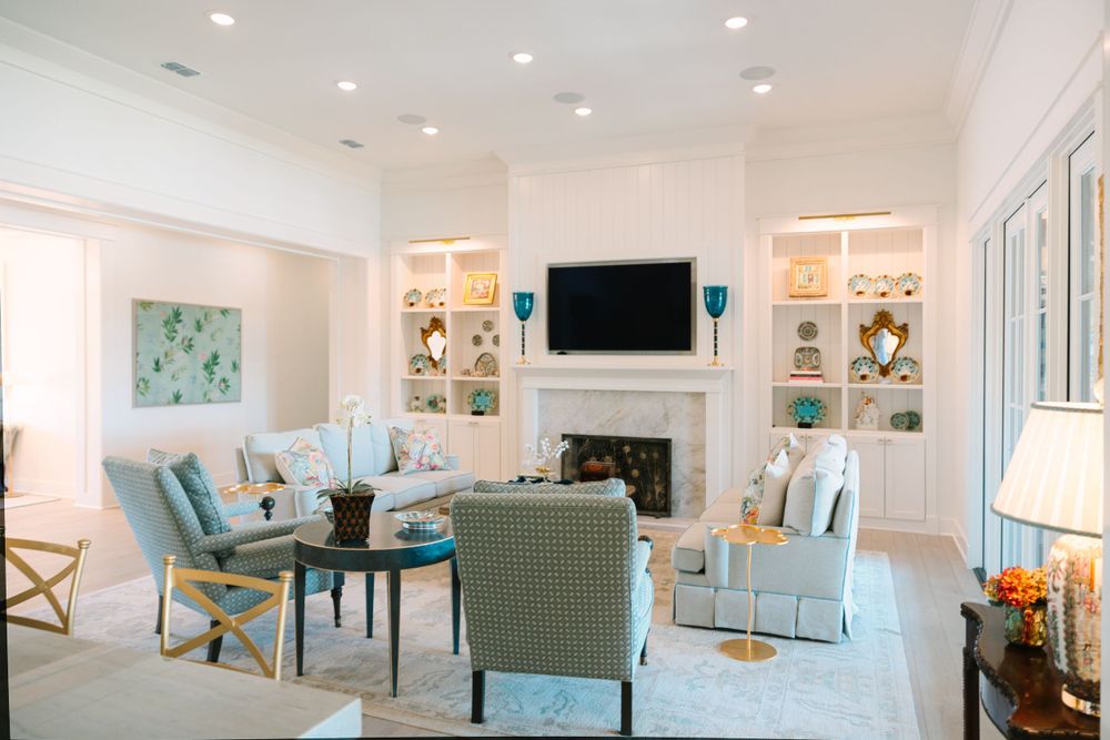 Elegant living room with coastal decor featuring blue accent chairs and built-in shelving around fireplace.