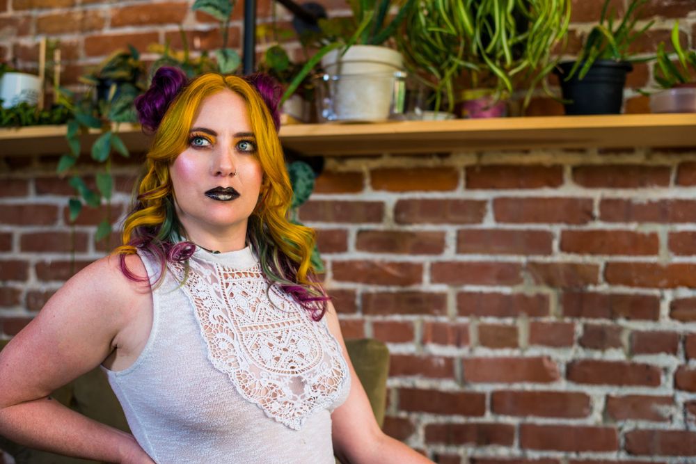 Interior portrait against exposed brick wall with plants and natural lighting.