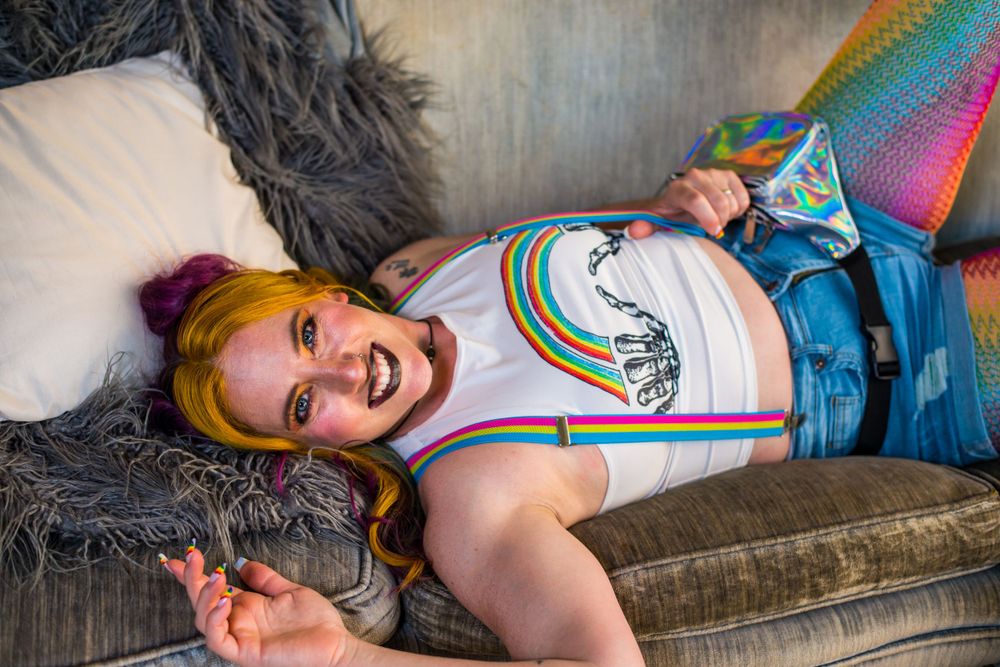 Colorful casual indoor portrait on grey couch with playful pose.