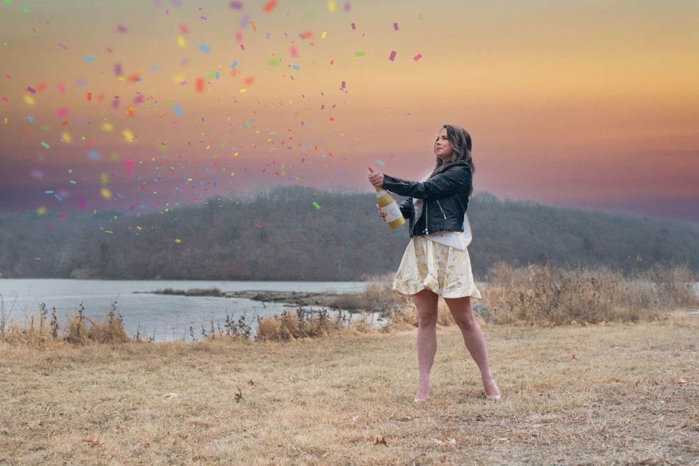 Colorful confetti fills the air during a sunset photoshoot by the ocean.