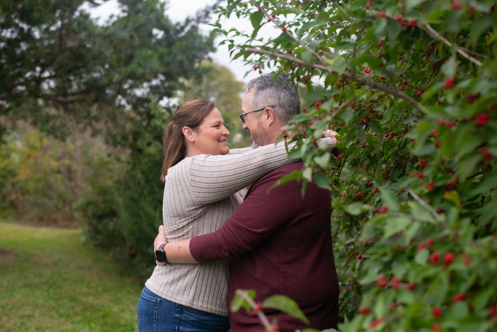 Romantic couple embracing under autumn trees in an outdoor setting.