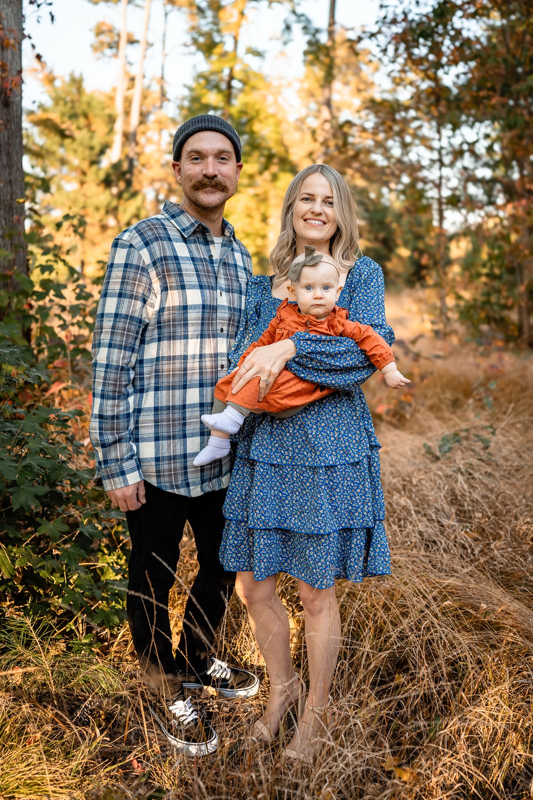 Outdoor autumn family portrait in wooded setting with golden sunlight.
