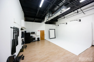 Spacious photo studio with wooden floors and professional lighting setup.