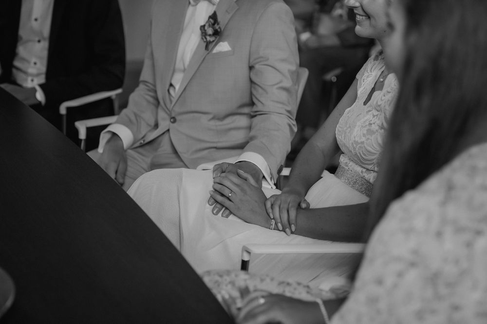 Black and white intimate moment captured during wedding ceremony showing couple holding hands.
