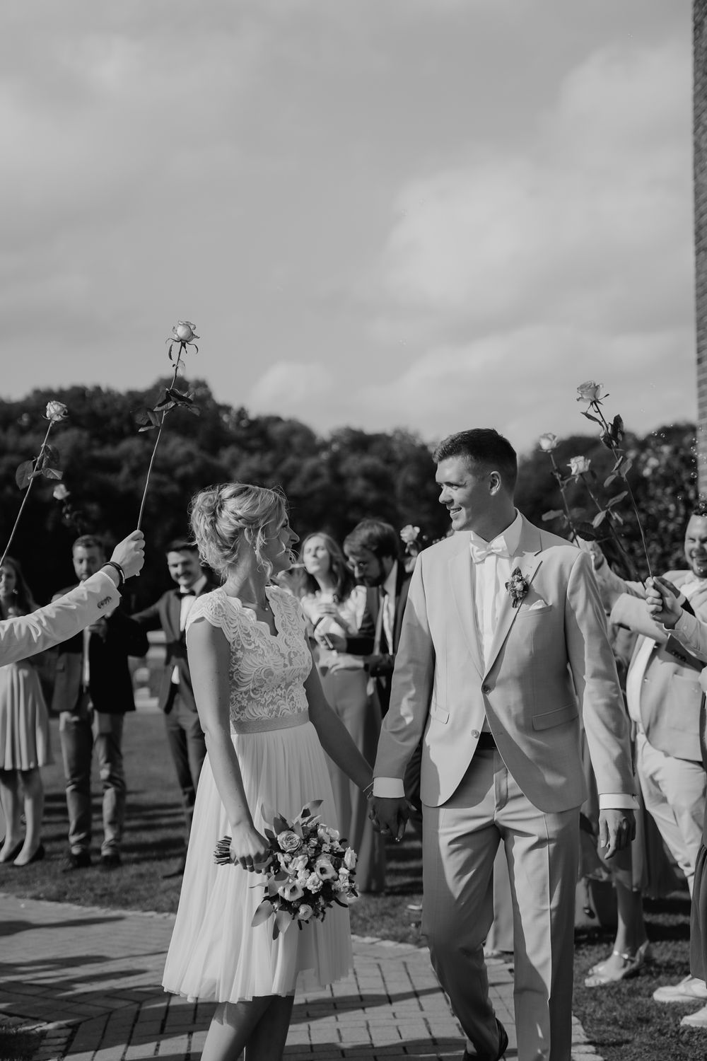 Wedding party lines pathway holding sparklers as couple walks through in elegant attire.
