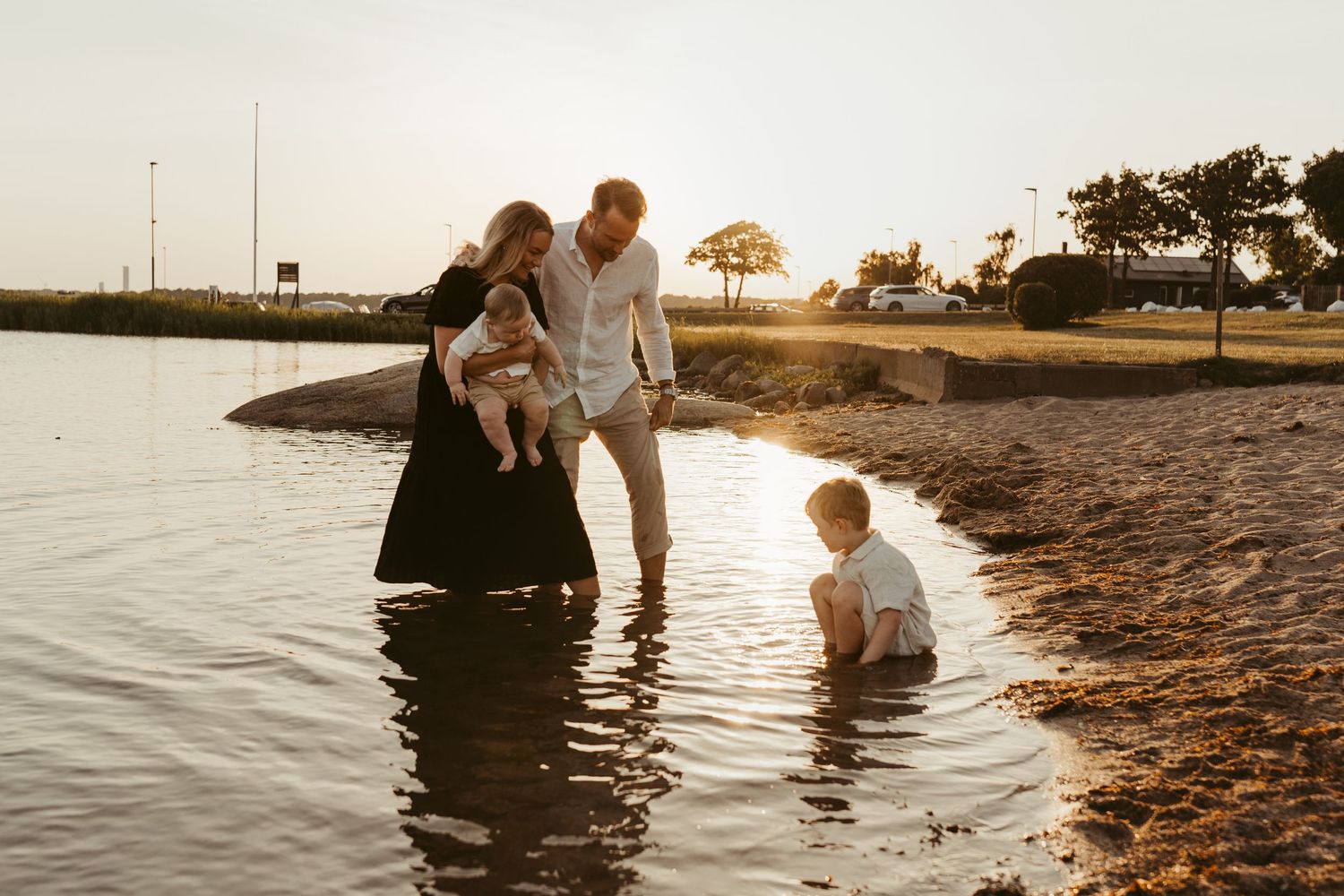 Family enjoying a sunset moment together at the beach shoreline.