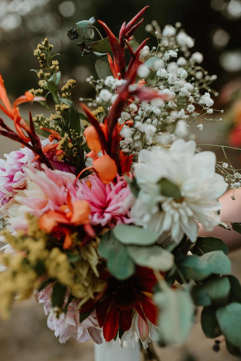 A vibrant wedding bouquet featuring pink, white, and red flowers with eucalyptus leaves.