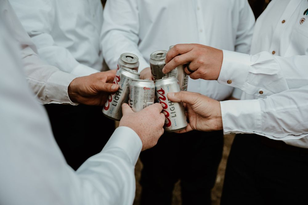 Multiple hands holding silver beverage cans together in a celebratory toast.