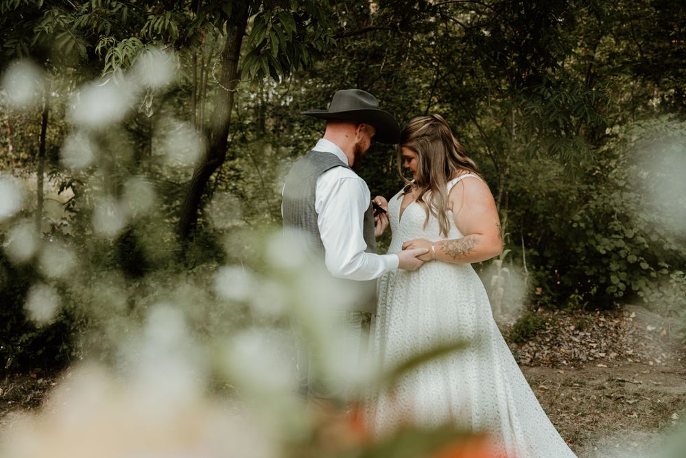 A couple shares an intimate moment in a dreamy outdoor garden setting at their western-themed wedding.
