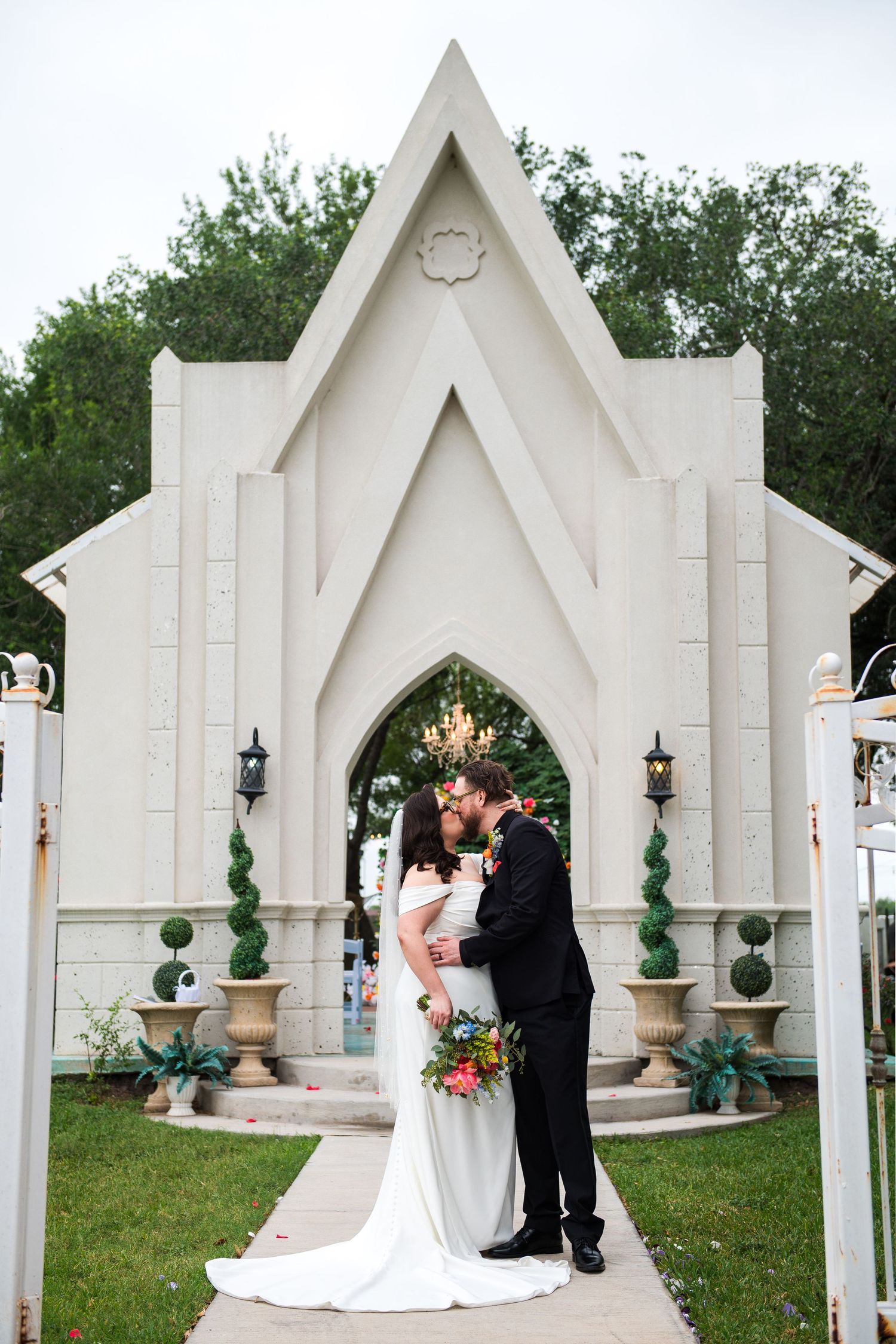 Tender moment between newlyweds against white floral backdrop during wedding celebration.