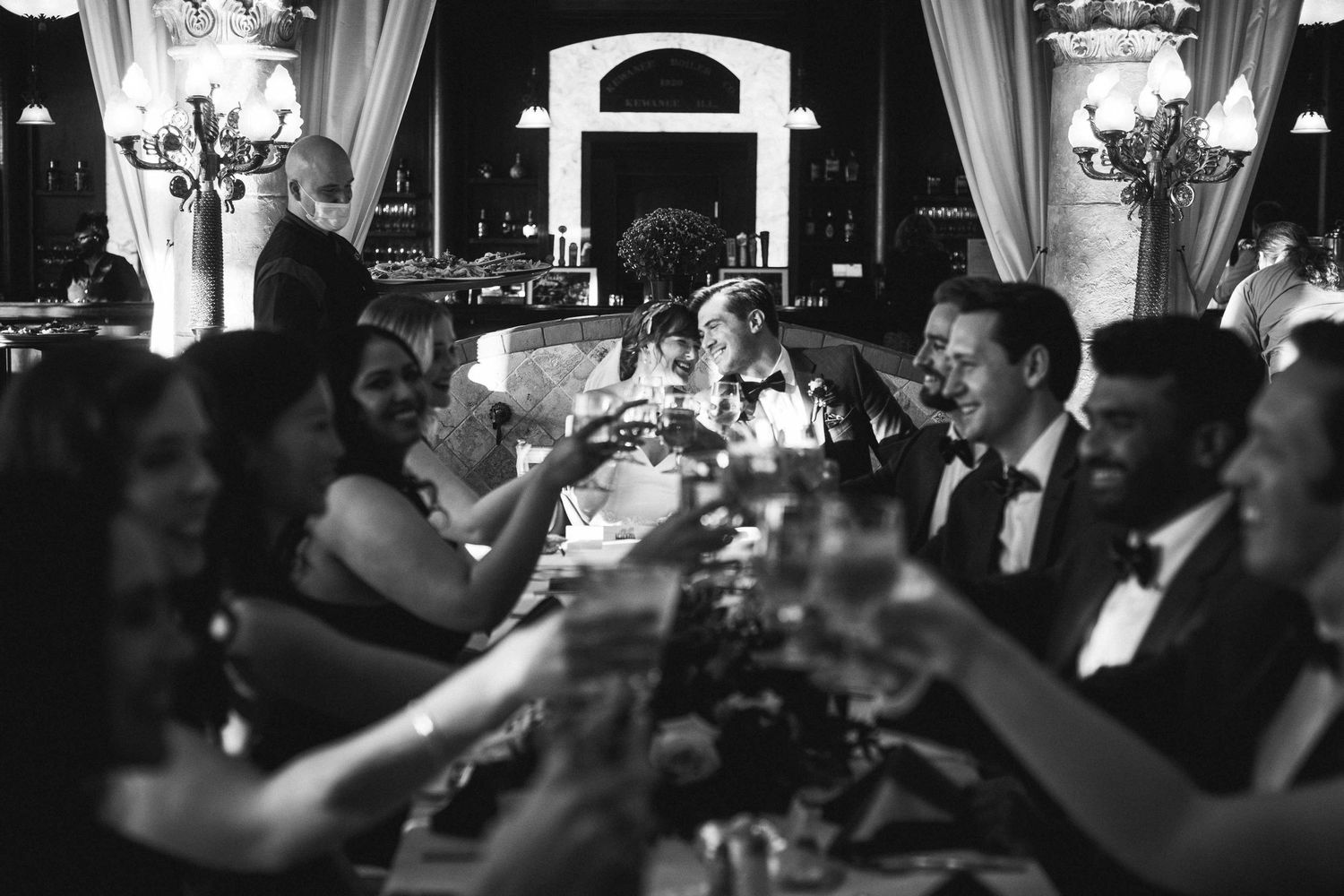 Wedding guests raise glasses in a toast during an elegant evening reception.