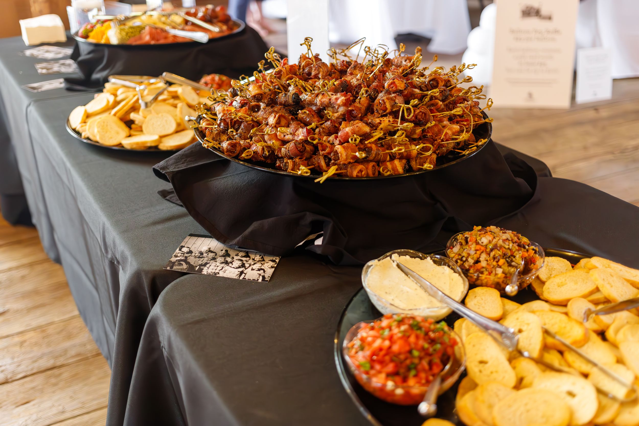 Catering buffet setup with tortilla chips and various party foods on black tablecloth.