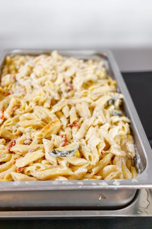 Creamy pasta salad with vegetables in aluminum catering pan.