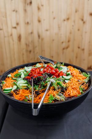 Fresh garden salad with shredded carrots and vegetables in black serving bowl.