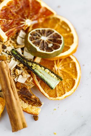 Close up of dried citrus slices with herbs on white marble surface showing texture and natural patterns.